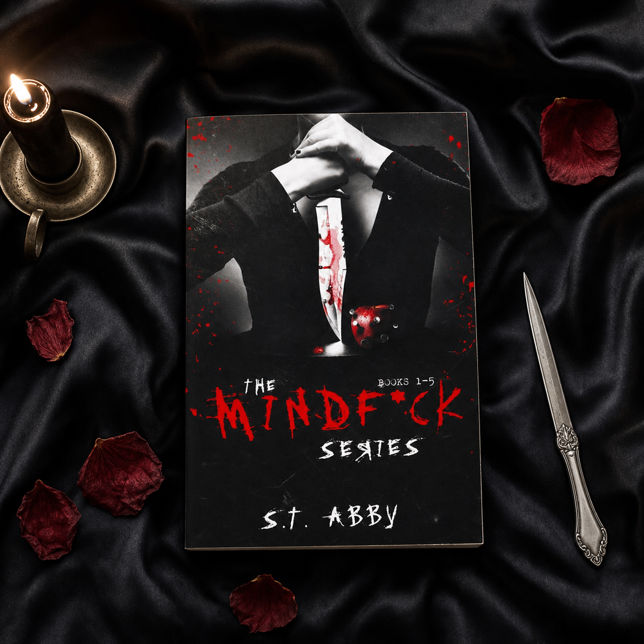 The Mindf*ck Series paperback flat lay on black sheets with a candle